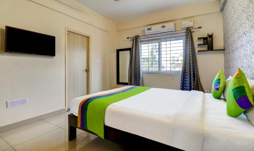 a bedroom with a large bed and a television at Treebo 12 Degrees West, Domlur in Bengaluru