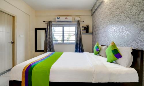 a bedroom with a large white bed with colorful pillows at Treebo 12 Degrees West, Domlur in Bengaluru