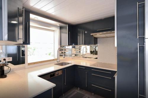 a kitchen with black cabinets and a large window at maison Vaïana in Saint-Pierre