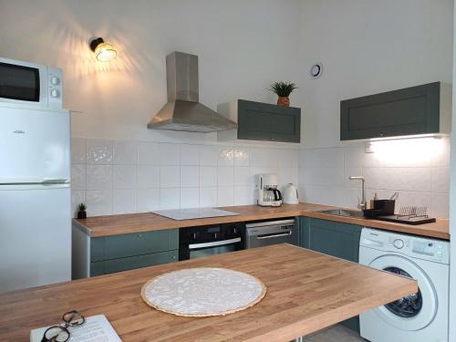 une cuisine avec une table en bois et un réfrigérateur blanc dans l'établissement Ardèche Horizon, Appartement climatisé avec Terrasse, Piscine et Parking, à Vallon-Pont-dʼArc