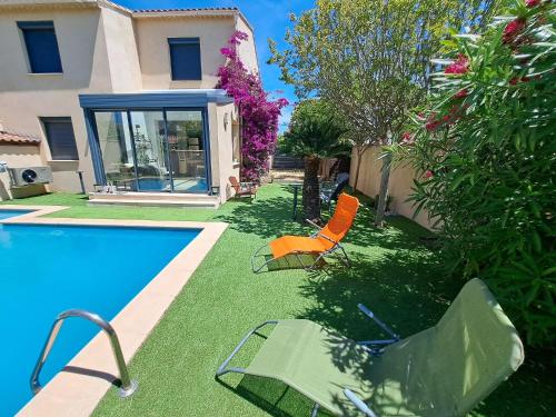 une piscine avec deux chaises à côté d'une maison dans l'établissement Villa cosy, à Six-Fours-les-Plages