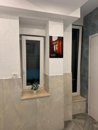 a room with two windows and a vase with flowers at LUXOR ECO ROMA CASA E APPARTAMENTO PER VACANZE IN CENTRO Piazza Bologna, Colosseo, Piazza di Spagna, Vaticano, San Pietro, Sapienza, Fontana di Trevi, Piazza Navona, Trastevere, Tiburtina, Termini, Aeroporto in Rome