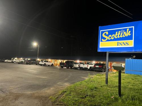 a sign in front of a parking lot at night at Scottis inns in Hurricane Mills