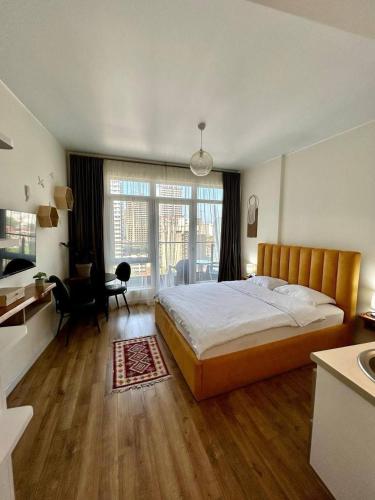 a bedroom with a large bed and a desk and a kitchen at Luxury Suites White Sails in Batumi