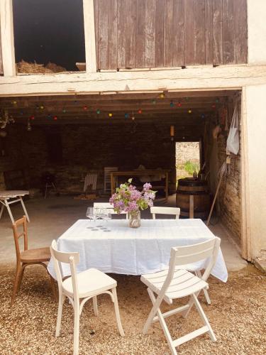 une table blanche avec des chaises et un vase de fleurs dans l'établissement Le Perchoir, à Auxey-Duresses