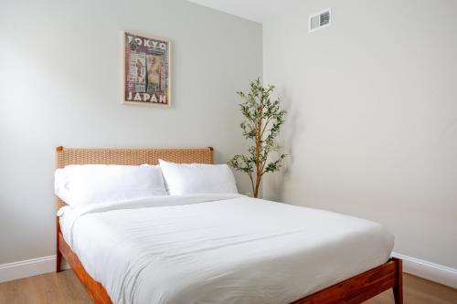 a bedroom with a white bed with a plant on it at Stylish Stay in Center City, French-Japanese & Minimalist Vibes in Philadelphia