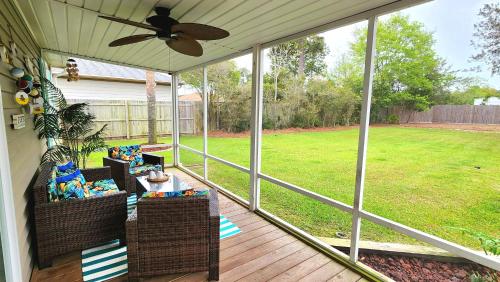 a screened porch with chairs and a ceiling fan at Poolside Palms Paradise in Navarre
