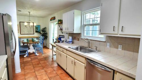 a kitchen with white cabinets and a sink and a table at Poolside Palms Paradise in Navarre