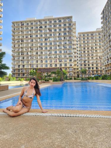 a woman in a bikini sitting next to a swimming pool at JL Condotel - Near Airport - Oceanview in Lapu Lapu City