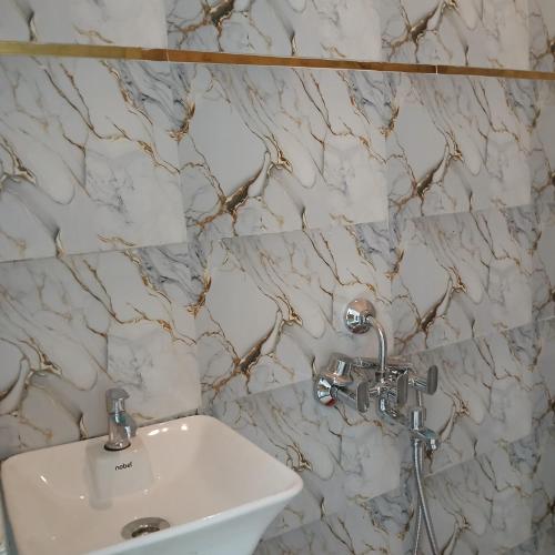 La salle de bains est pourvue d'un lavabo blanc et de murs en marbre. dans l'établissement Awadh Biharee Inn, à Ayodhya