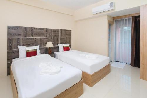 two beds in a white room with a window at Good View Residence in Lampang