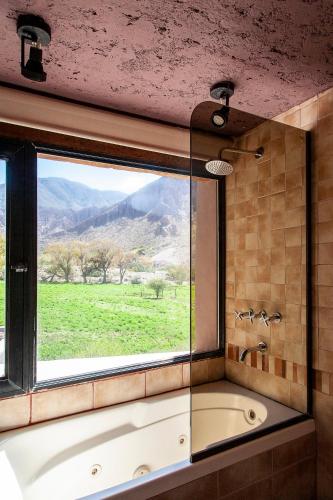 a bathroom with a tub and a window with a view at La Comarca Hotel in Purmamarca