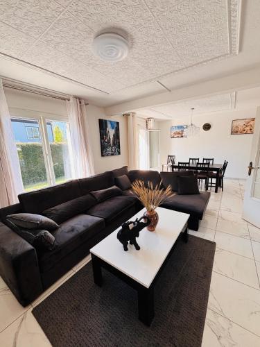 un salon avec un canapé noir et une table dans l'établissement Le Pavillon G aillard - Maison de 5 chambres, à Gien