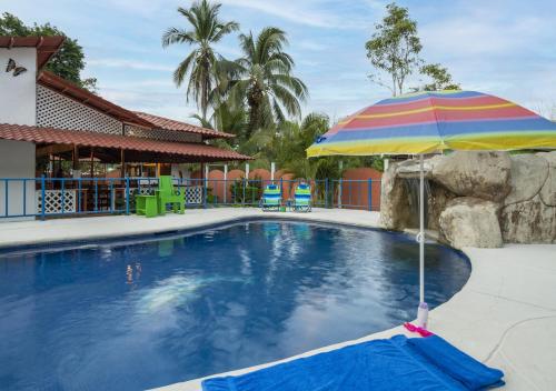 a pool with an umbrella and a swimming pool at Entire Home Near Beach, Quiet Area, Pool in Manzanillo
