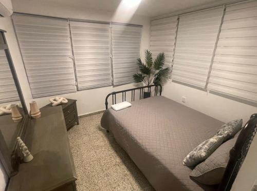 a bedroom with a bed and windows with blinds at Casa Ramos in Aguadilla