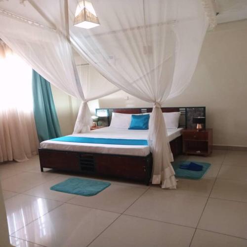 a bedroom with a bed with a mosquito net at The Abode2 Entebbe in Entebbe