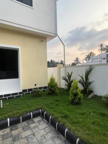 a backyard of a house with a green lawn at WHITE COTTAGE- Deluxe villa in Udupi