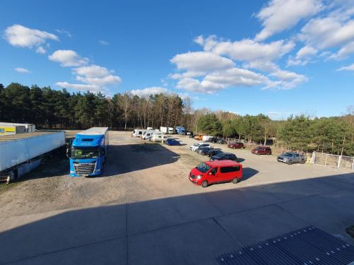 a parking lot with a red car and a blue truck at Akdeniz Pension in Ludwigsfelde