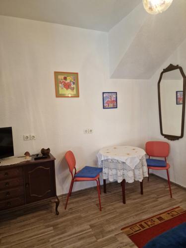 a room with a table and two chairs and a mirror at apartman Luisiana in Lukovdol