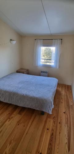 a bedroom with a bed with a wooden floor and a window at Maisonnette Sous les chênes GARD 30 in Sauve