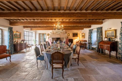 a dining room with a table and chairs and a chandelier at La Bastide in Oppède