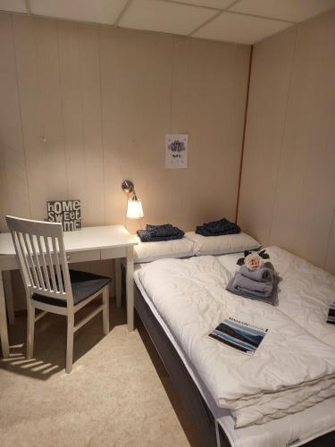 a room with two beds and a desk and a chair at Koselig Leilighet i Narvik sentrum 5 Soveplasser Gratis parkering og Gratis internet in Narvik