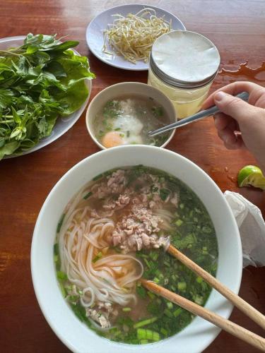 a table with a bowl of soup and a bowl of food at MOONLIGHT Homestay & Hotel in Pleiku