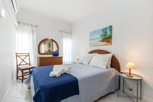 een slaapkamer met een bed, een stoel en een spiegel bij Vieira Casino in Armação de Pêra