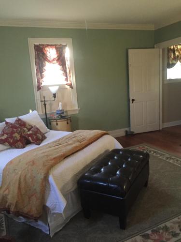 a bedroom with a large bed with a black ottoman at Stephen Clay Homestead Bed and Breakfast in Candia