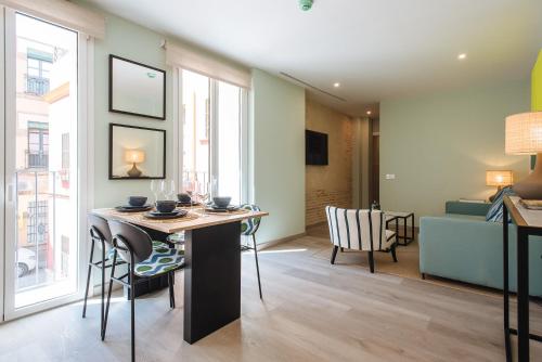 a living room with a table and chairs and a couch at Sercotel Sevilla Guadalquivir Suites in Seville