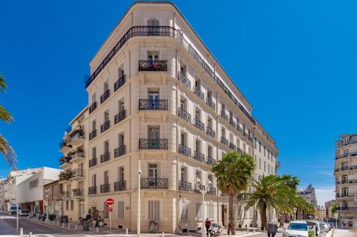 a tall white building with palm trees in front of it at Ô Repos des artistes - Balcon & Spa in Toulon