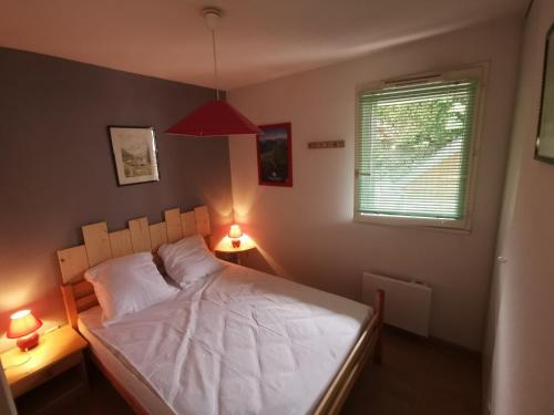 - une chambre avec un lit avec des draps blancs et 2 lampes dans l'établissement T3 Cosy de plein pied Terrasse Jardin Luchon Pyrénées, à Luchon