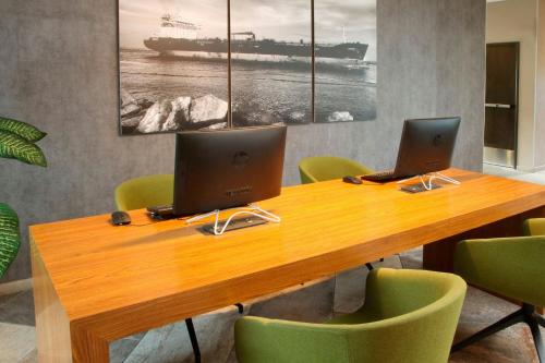 two laptops on a wooden table with green chairs at City Express Plus by Marriott Tampico in Tampico