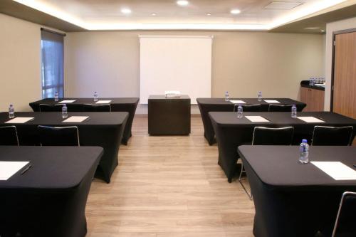 a conference room with black tables and chairs and a whiteboard at City Express Plus by Marriott Tampico in Tampico