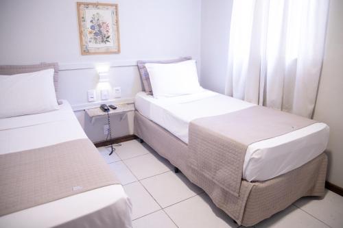 a hotel room with two beds and a window at Hotel BH Palace in Belo Horizonte