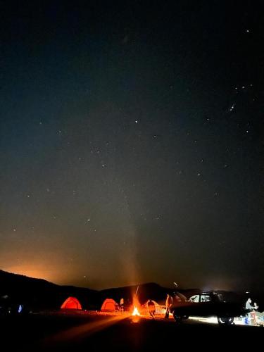 a group of tents and a fire at night at Dana to Petra Hiking Camping in Dana