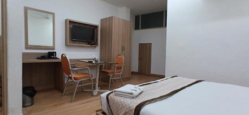 ニューデリーにあるHotel The Metropolitan Plaza Near IGI Airport Delhiのベッドとテーブルと椅子のあるホテルの部屋
