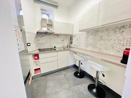 a kitchen with white cabinets and stools in it at "Sweet Life" Casa Vacanze in Lipari
