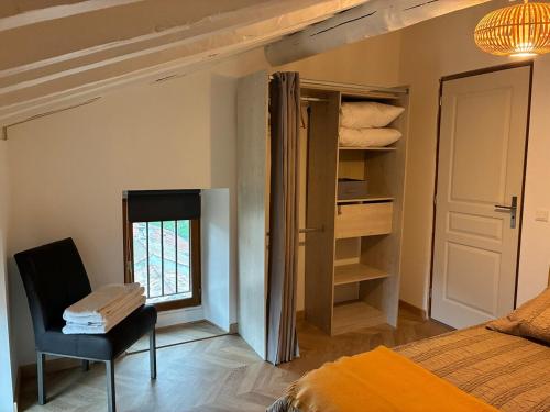 une chambre avec un lit, une chaise et une fenêtre dans l'établissement Appartement Sainte Lucie de Tallano,2 personnes au centre du village, à Santa-Lucia-di-Tallano