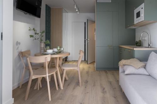 a kitchen and dining room with a table and chairs at Apartamenty Wyspa Jastarnia Oliwkowy in Jastarnia