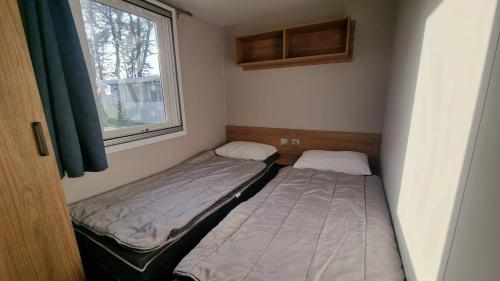 two beds in a small room with a window at Charmant bungalow à Piriac-sur-Mer avec piscine partagée in Piriac-sur-Mer