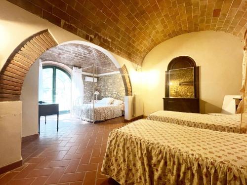 a bedroom with two beds and a desk in a room at Relais Casale Il Poggetto VILLA PAOLA by Zoom In Earth in Cecina