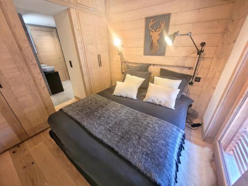 une chambre avec un lit dans une pièce aux murs en bois dans l'établissement Appartement prestigieux au centre avec cheminée, 6 pers, sauna, hammam, fitness, parking - FR-1-598-151, aux Gets