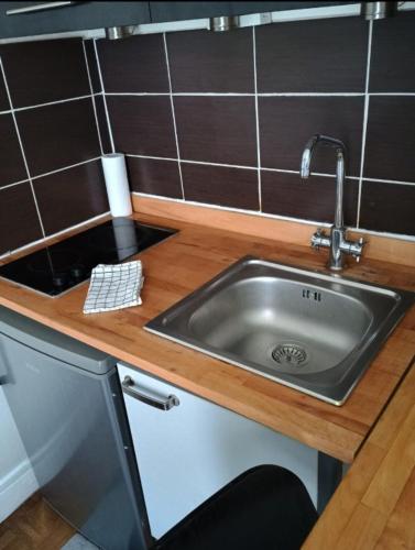 un évier en acier inoxydable dans une cuisine avec du carrelage brun dans l'établissement Le Napoleon Paris Invalides Chambre Independante, à Paris