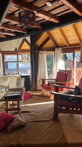 a living room with couches and tables and windows at HOSTEL CASA C Alojamiento, Coworking y Centro Cultural in Villa General Belgrano