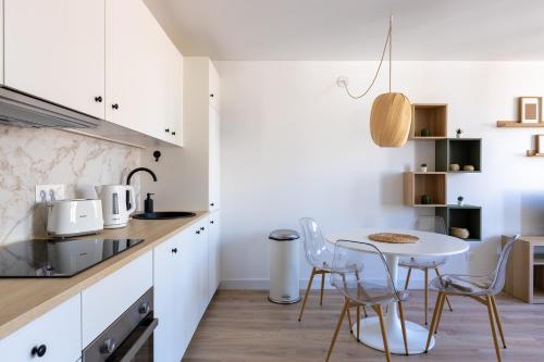 une cuisine avec des armoires blanches et une table et des chaises dans l'établissement Huiliers Cosy spot - Metz hyper centre, à Metz