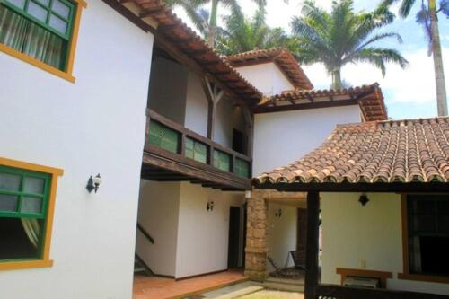 a white building with a tiled roof and palm trees at OYO Pousada do Wagner, Rio das Ostras in Rio das Ostras