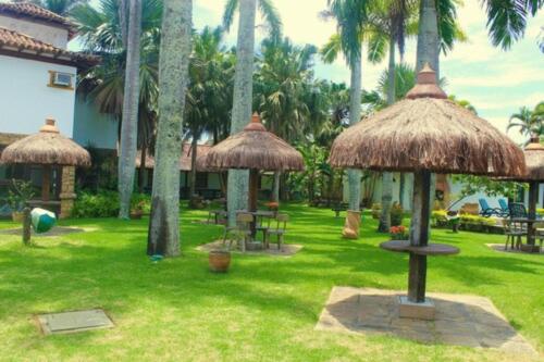 a resort with palm trees andiki umbrellas in a yard at OYO Pousada do Wagner, Rio das Ostras in Rio das Ostras