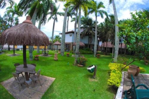 a yard with a table and a straw umbrella at OYO Pousada do Wagner, Rio das Ostras in Rio das Ostras