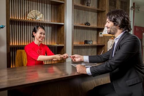 a man and a woman shaking hands at a table at The Bloom Hanoi - Bespoke Living in Hanoi